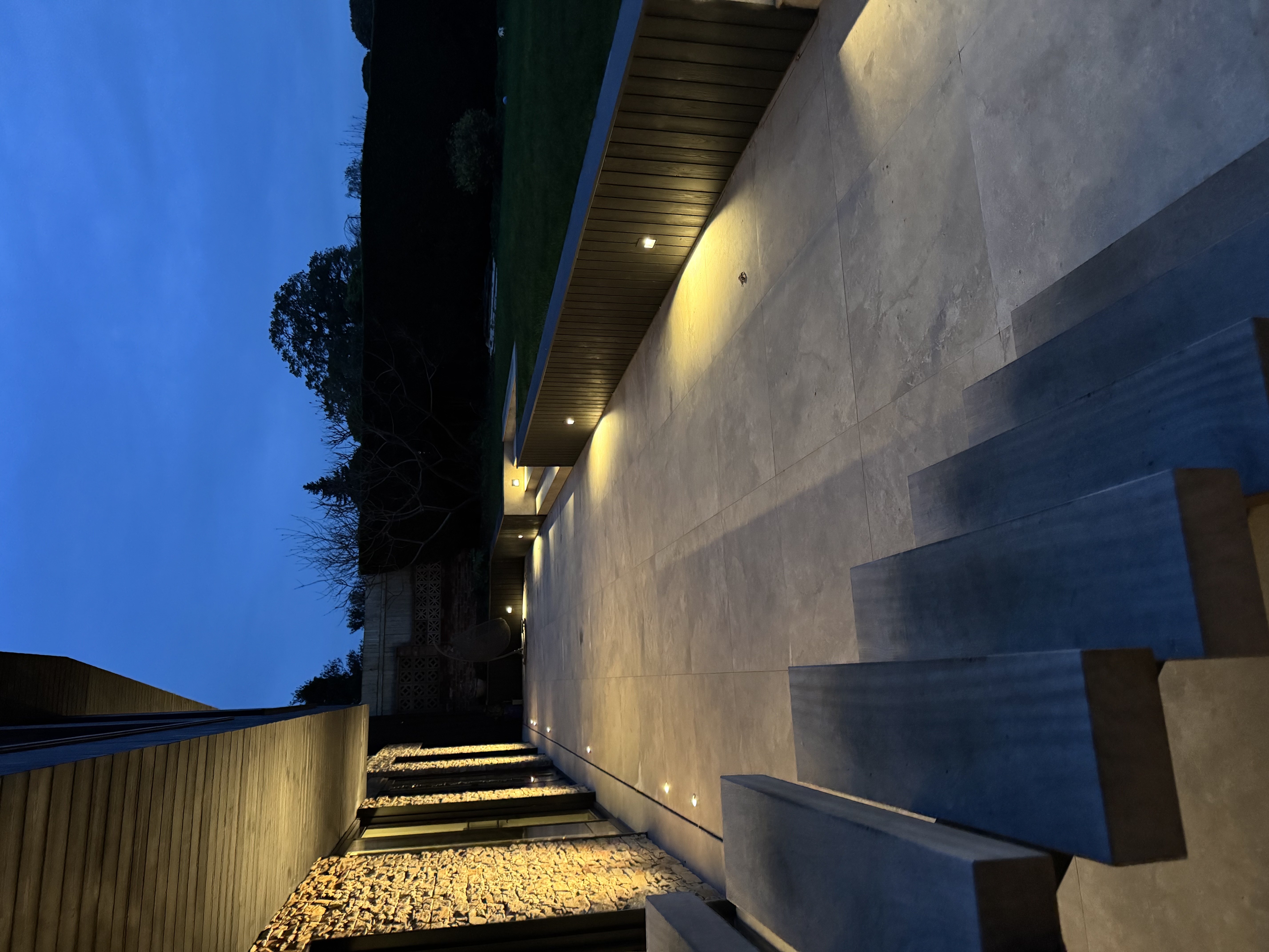 Recessed ground lights illuminating a luxury stone terrace and steps at dusk — electrical installation by ProConform
