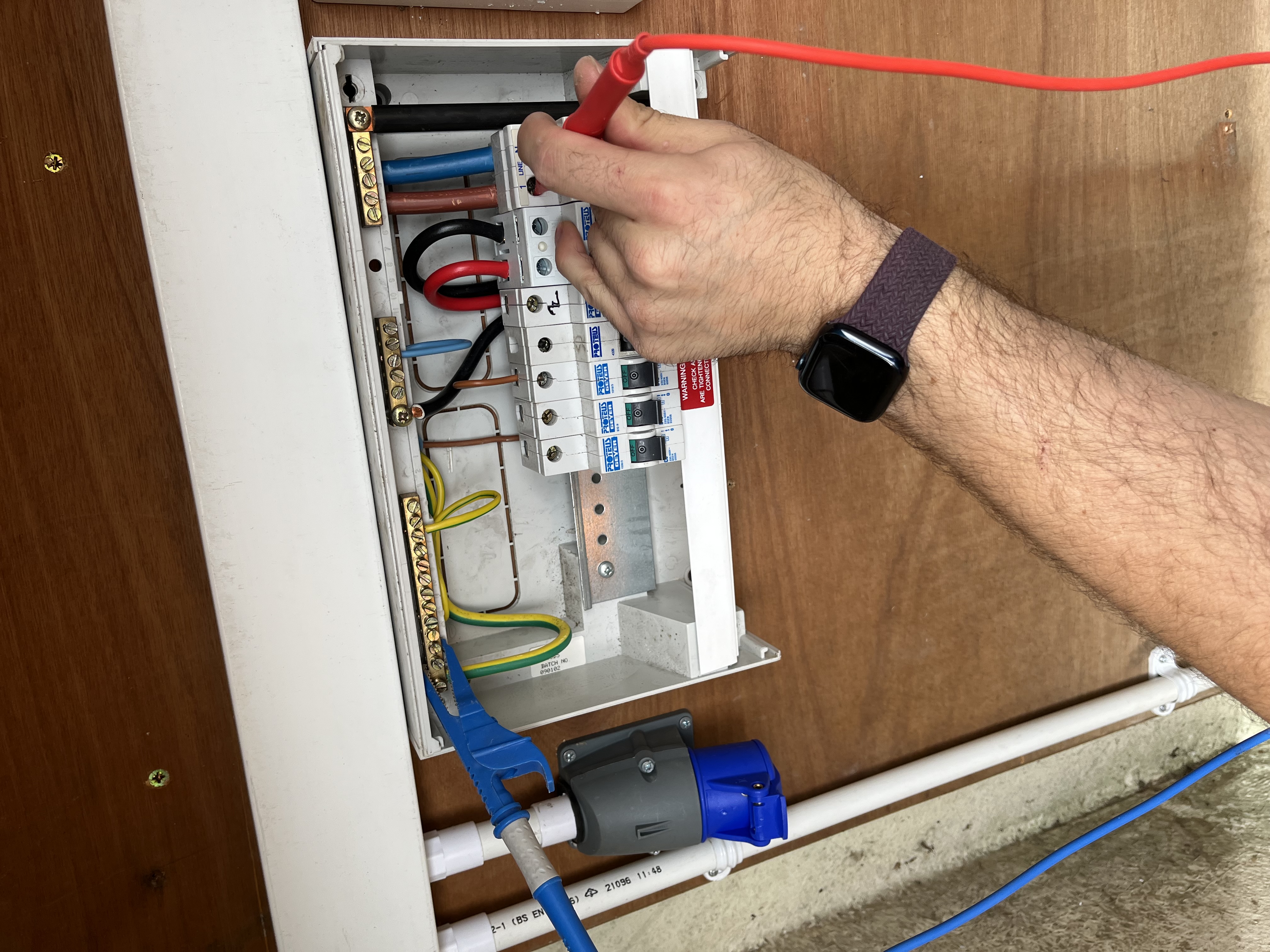ProConform engineer applying test probes to a consumer unit sub-board during post-installation testing